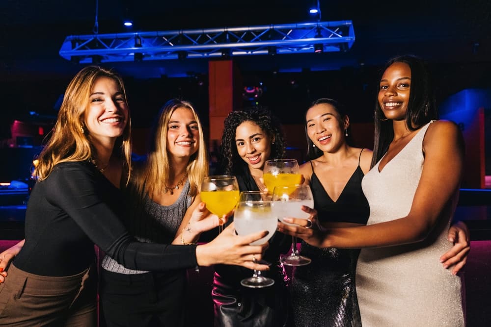 Group of women toasting with cocktails at a Las Vegas nightclub during a hip hop club crawl